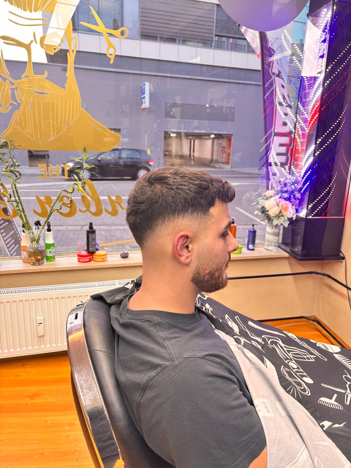 Kunde im Barber-Stuhl mit goldenem Schaufenster-Logo